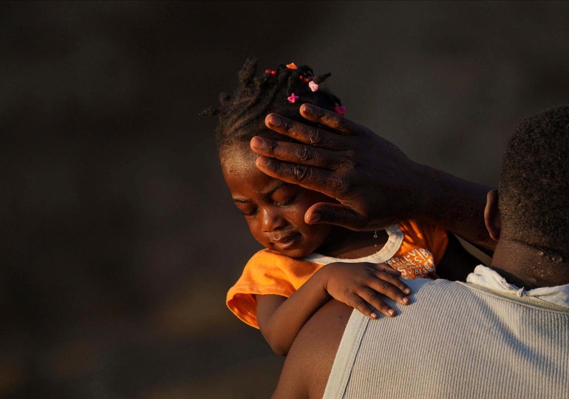 A man carries a girl across the Rio Grande river as migrants, many from Haiti, leave Del Rio, Texas, to return to Ciudad Acuna, Mexico, early Wednesday, Sept. 22, 2021, to avoid possible deportation from the U.S.