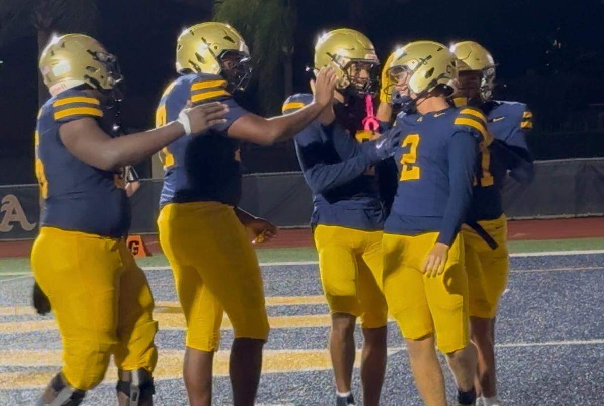 St. Thomas Aquinas quarterback Andrew Indorf is congratulated by teammates after his second touchdown run in Friday’s night’s win over Monarch.