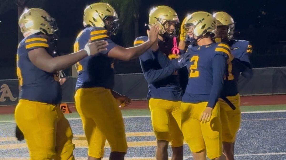 St. Thomas Aquinas quarterback Andrew Indorf is congratulated by teammates after his second touchdown run in Friday’s night’s win over Monarch.
