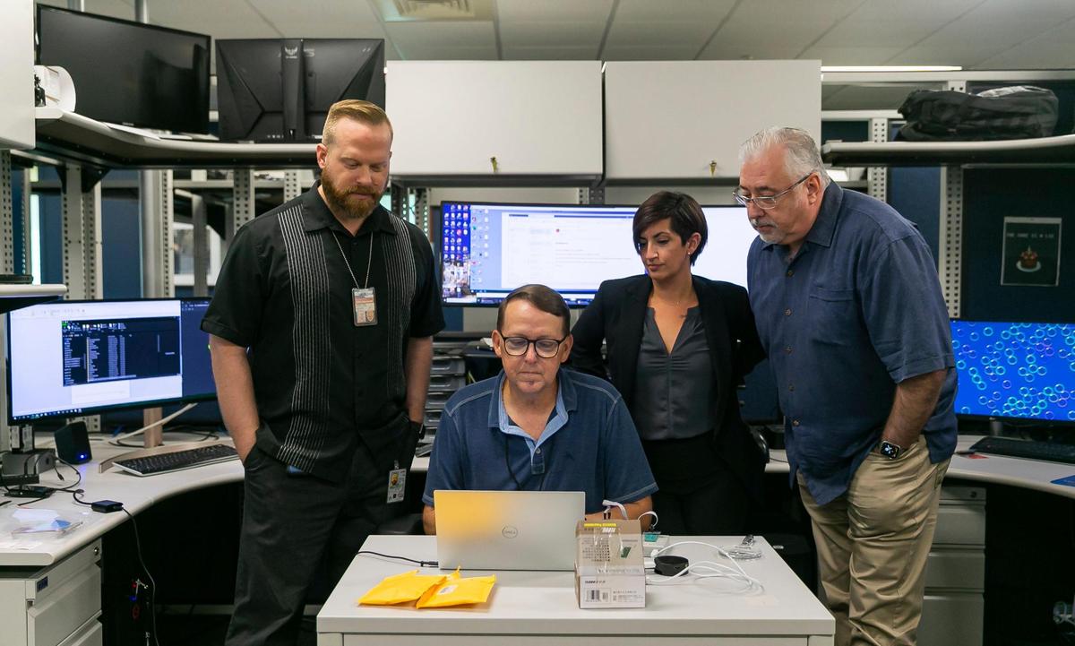 From left, Miami-Dade Police Lt Jordan Fried, Officer Tracy Tompkins, Sgt. Bridget Doyle and Maj. George Perera, all with the South Florida Cyber Crimes Task Force, inspect an electronic skimmer at their office.