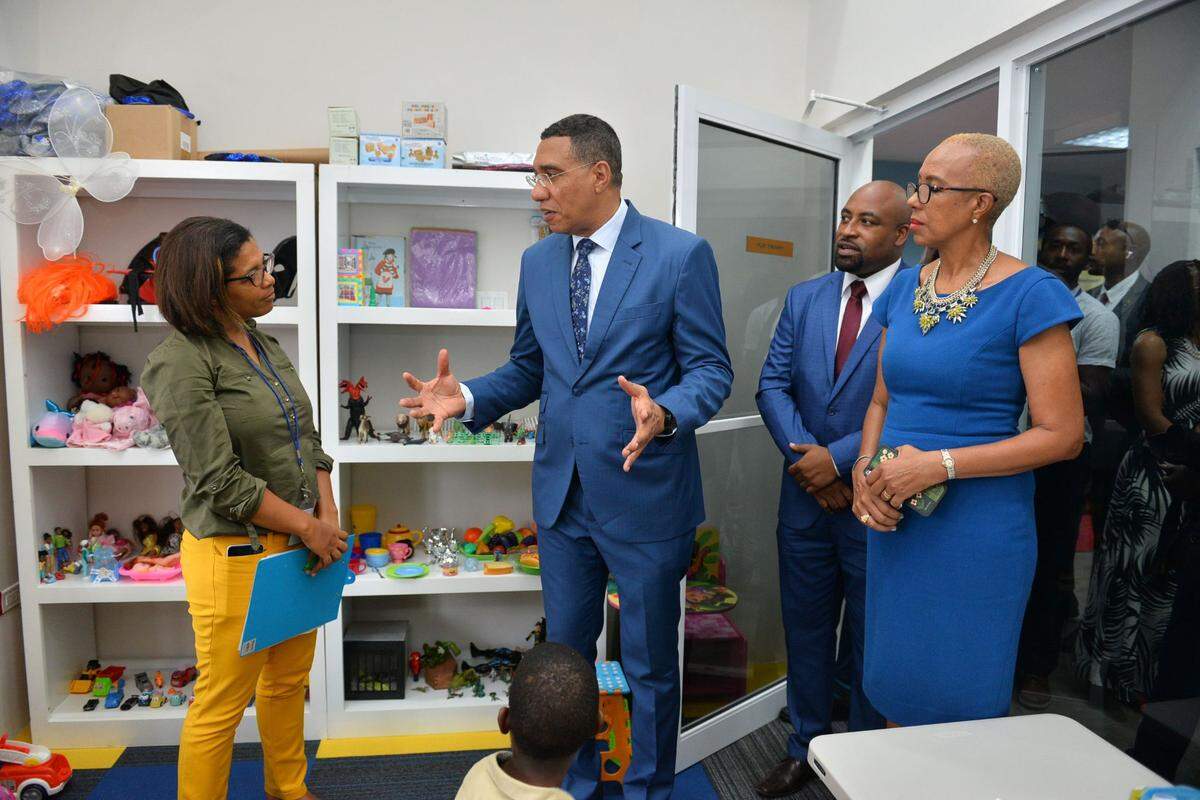Jamaica Prime Minister Andrew Holness, center, on a visit with a child psychologist in the country where violence involving children is increasingly becoming a concern.