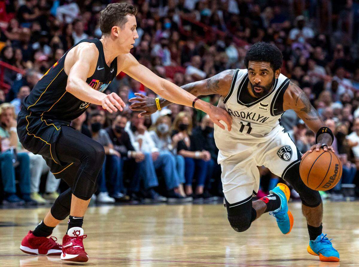 Brooklyn Nets point guard Kyrie Irving (11) drives on Miami Heat forward Duncan Robinson (55) during the fourth quarter of an NBA game at FTX Arena in Miami on Saturday, February 12, 2022.