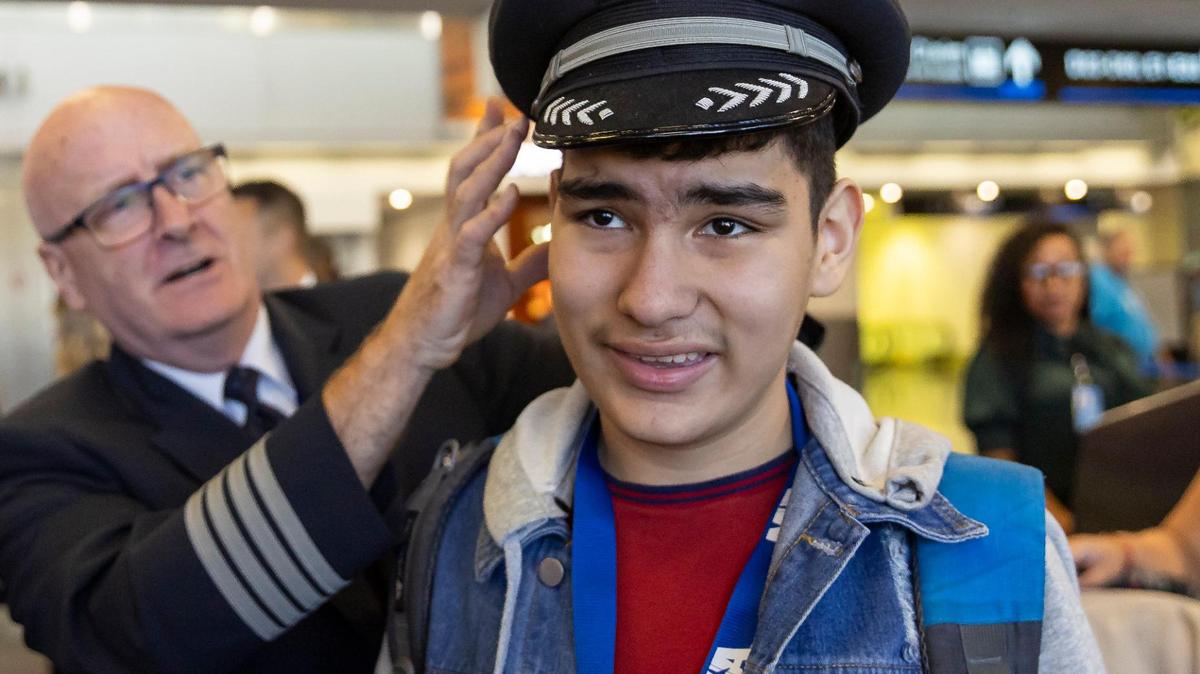 American Airlines Captain Christopher Kent places his cap on 13-year-old Samuel Castillo’s head during the MIAair tour at the Miami International Airport on Monday, Oct. 23, 2023, in Miami, Fla. The MIA Airport Instruction and Readiness tour allows about 25 children with special needs to walk through an airport travel experience from start to finish in a safe and controlled environment.