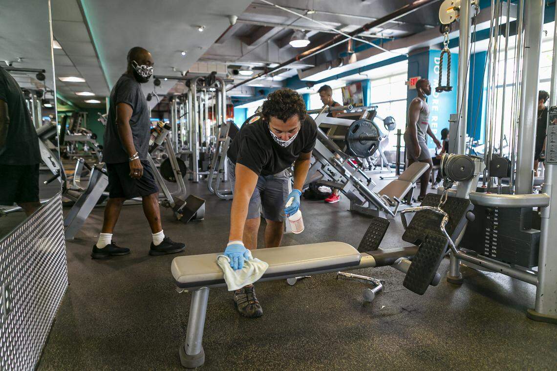Ivan Granados, 26, a Clean Team member at Crunch Fitness, disinfects a workout station in their Miami Beach location on Monday, June 8, 2020. Miami-Dade officials lifted a ban that prevented gyms from operating because of the coronavirus pandemic.