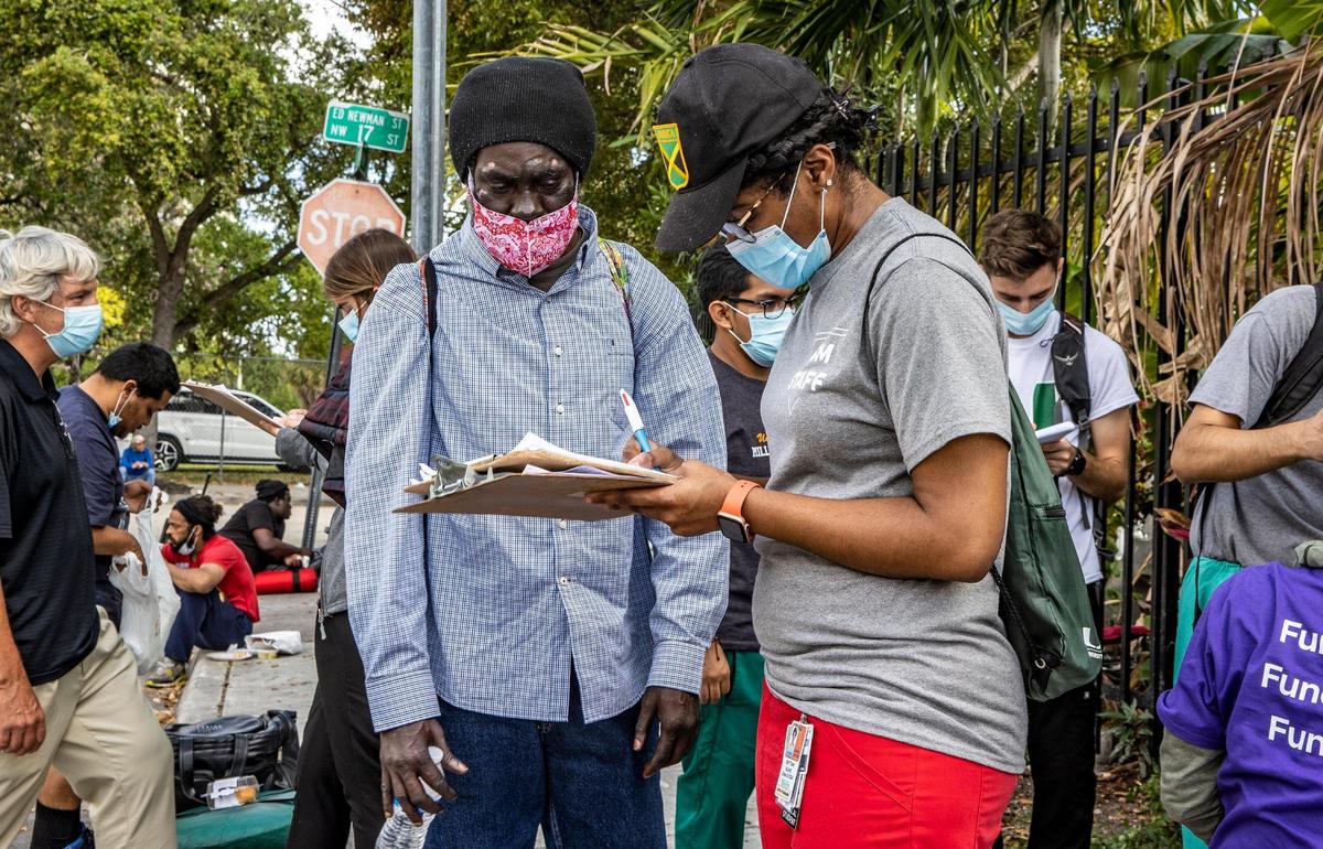 University of Miami medical student Brittany Blake, right, a member of the Miami Street Medicine team, gets information from Eddy during their weekly rounds along Northwest 17th Street in Miami, on March 5, 2022. The Miami Street Medicine is a mobile clinic launched by Dan Bergholz, a third-year student at the Miller School of Medicine at UM, to treat Miami’s homeless community.
