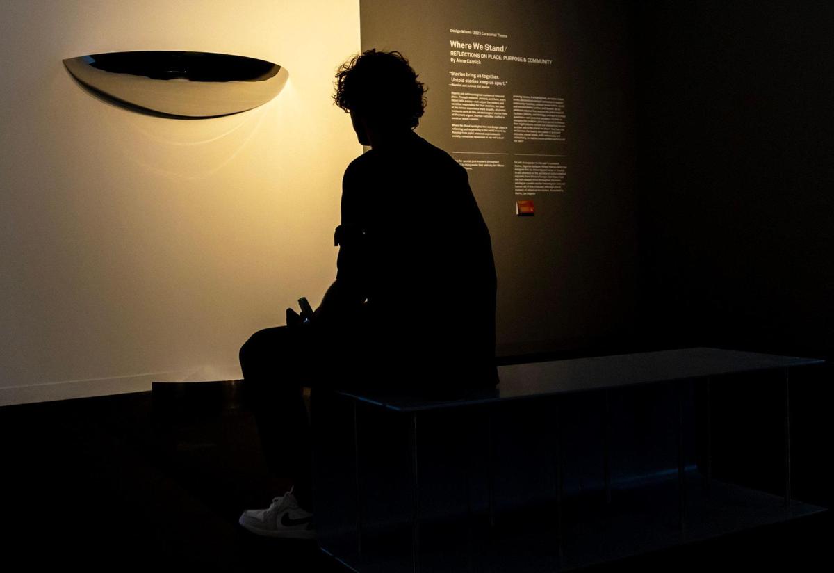 A man sits and stares at “Reflections On Place” artwork by Anna Carnick, representing the 2023 Curatorial Theme of Where We Stand, during the VIP opening of Design Miami for Art Basel in Miami Beach, Florida, on Tuesday, December 5, 2023.