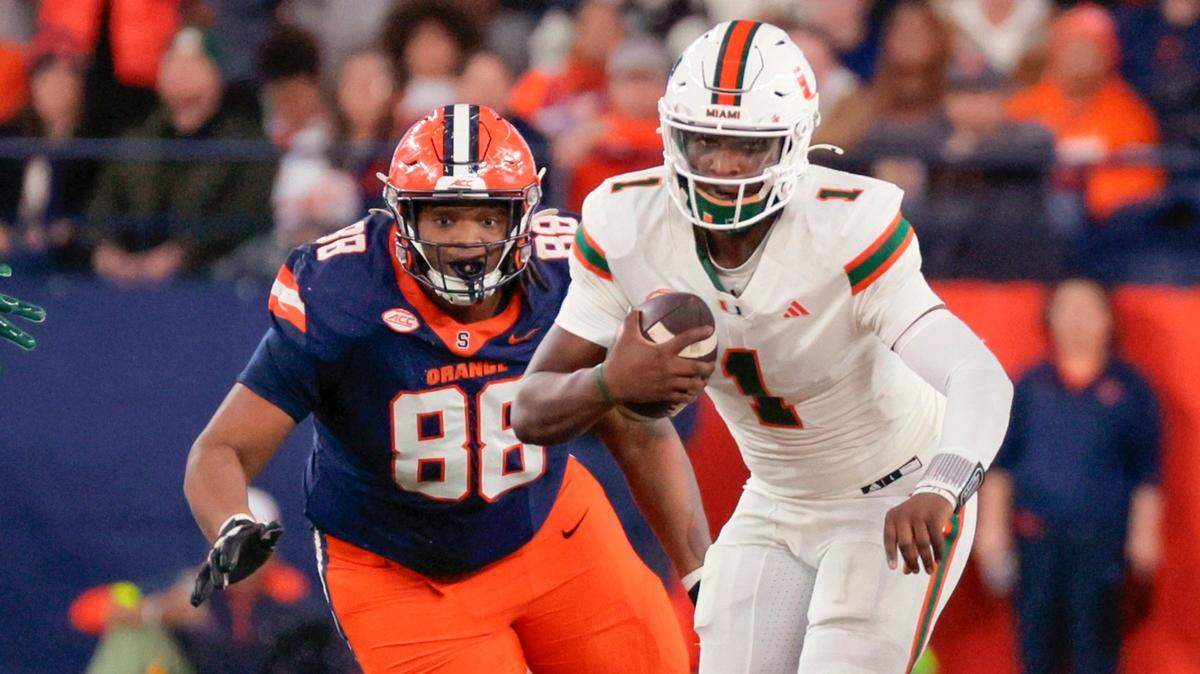 Miami Hurricanes quarterback Cam Ward (1) on the run as Syracuse Orange defensive lineman Maraad Watson (88) gives chase in the second half of their NCAA football game in the JMA Wireless Dome at Syracuse University, Syracuse, New York on Saturday, November 30, 2024.