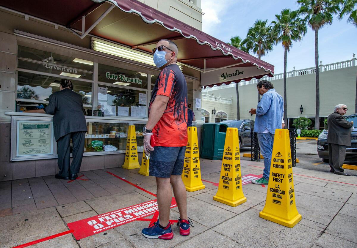 Social distancing is enacted at La Ventanita as patrons wait their turn, six feet apart, to order Cuban coffee and pastries at Cafe Versailles on April 1, 2020. The popular Cuban restaurant in Miami is open for takeout service only during the COVID-19 pandemic.