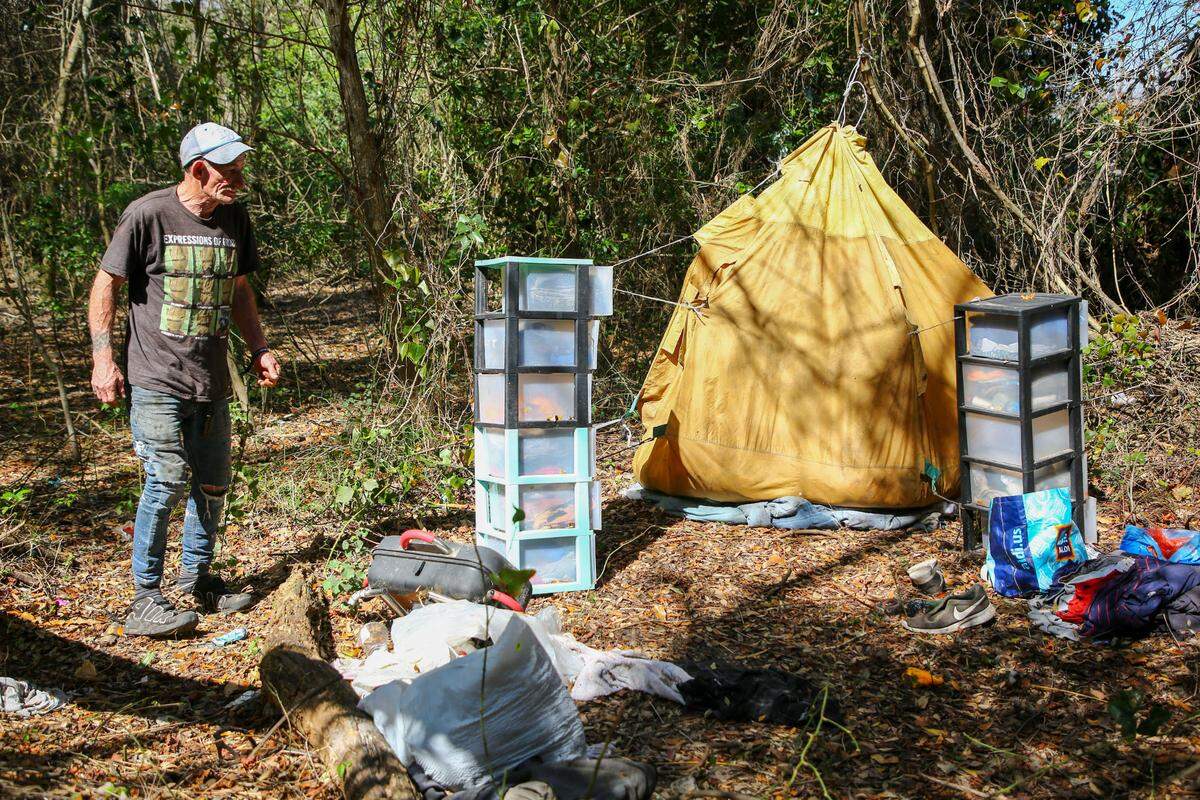 Joe Cornell, 61, tends to his homeless encampment on a rural tract of land off Rowan Road on Tuesday, Feb 27, 2024, in New Port Richey. Cornell, who has been homeless for a year, said he has had a difficult time finding employment.
