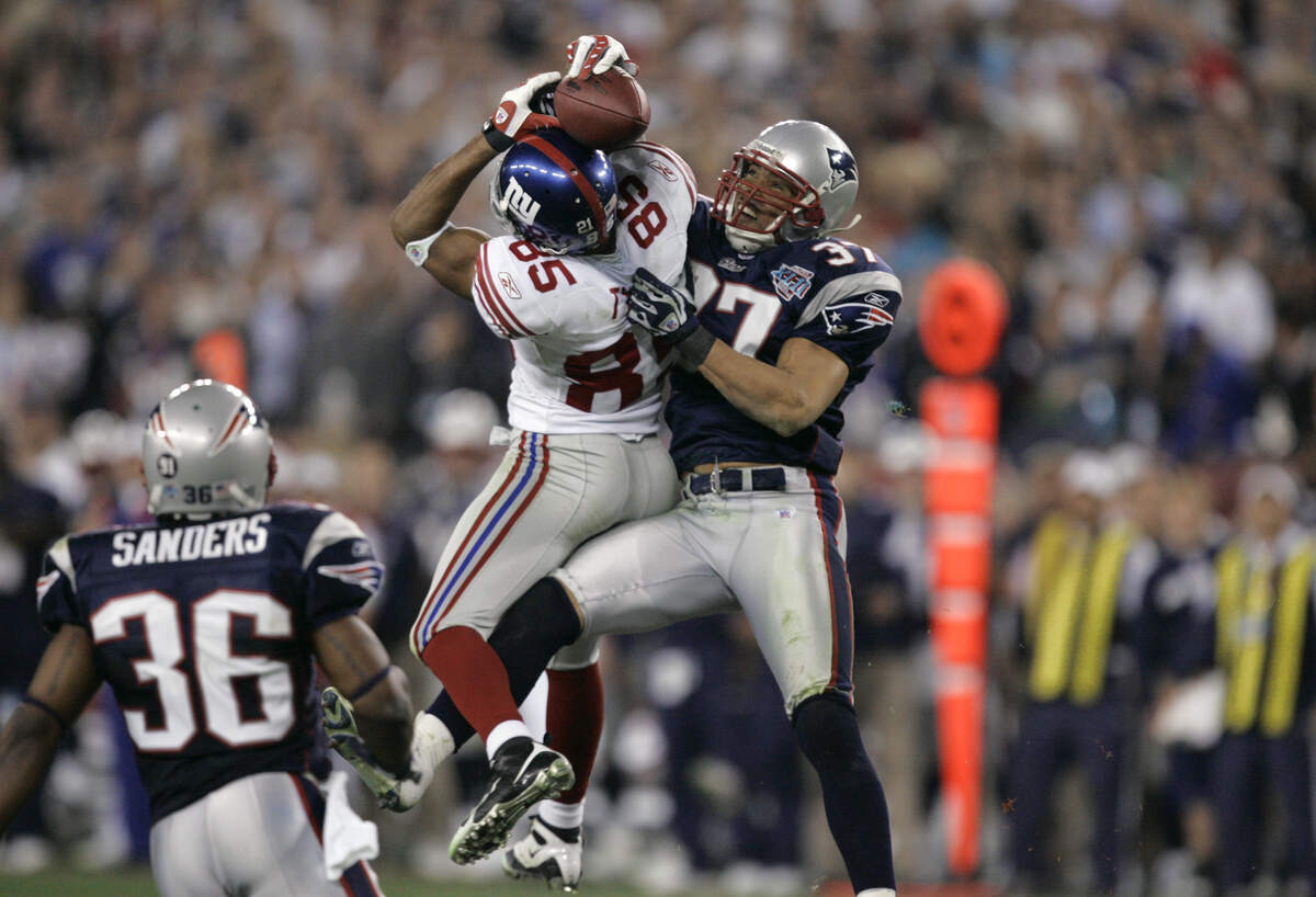 New York Giants receiver David Tyree (85) catches a 32-yard pass in the clutches of New England Patriots safety Rodney Harrison (37) during the fourth quarter of the Super Bowl XLII in Glendale, Arizona, in 2008. The Giants won 17-14.