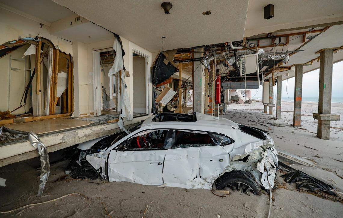 A damaged Lamborghini sits under a house two days after several feet of beach sand washed ashore from hurricanes Helene and Milton.