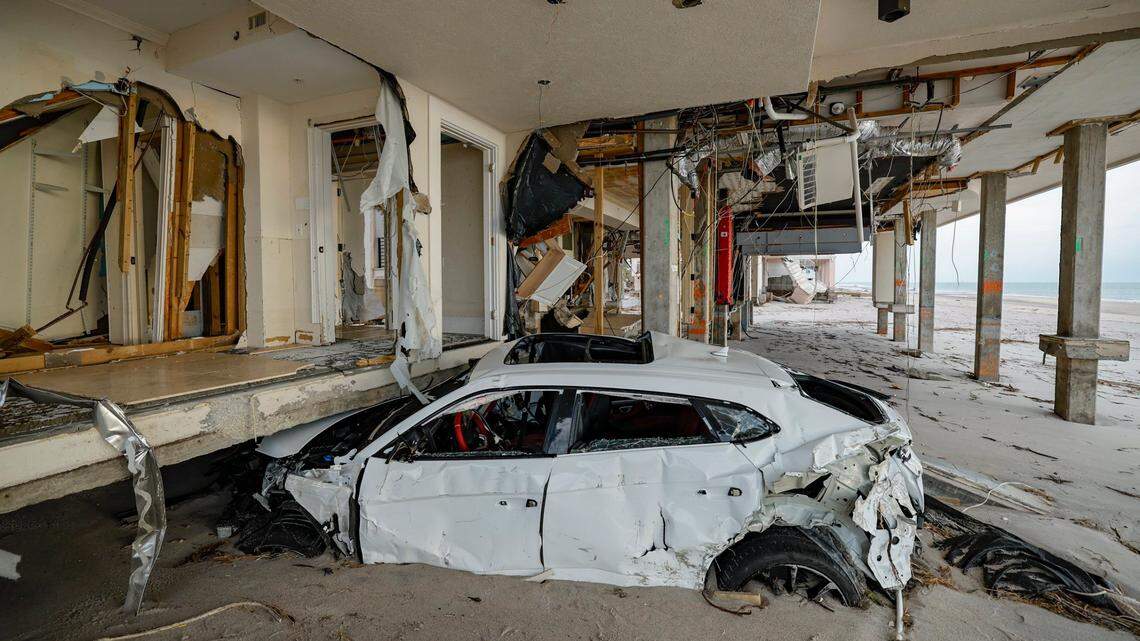 A damaged Lamborghini sits under a house two days after several feet of beach sand washed ashore from hurricanes Helene and Milton.