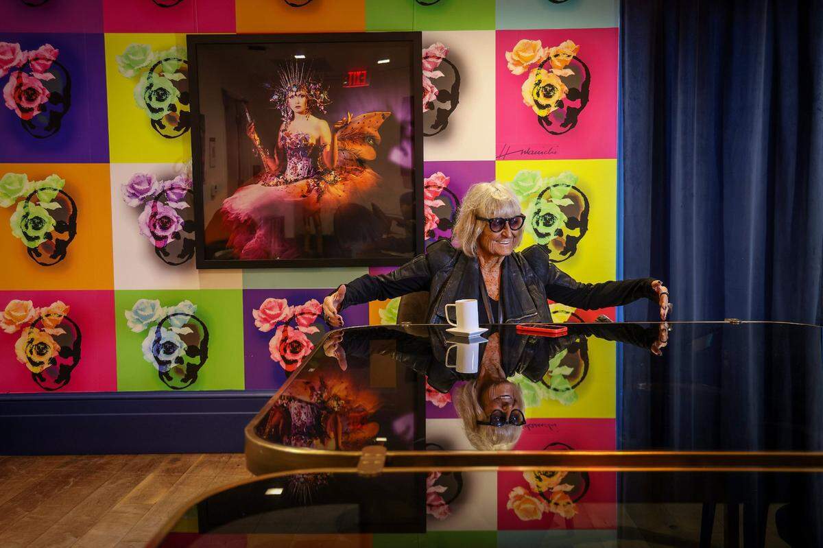 Barbara Hulanicki enjoys a cup of coffee inside the Betsy Hotel, which features wallpaper and a photo of the dress she designed.