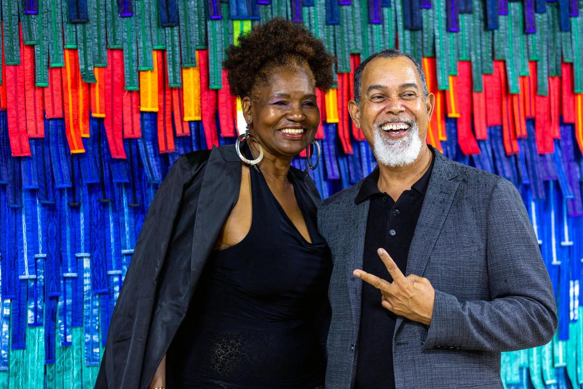 Donovan and Myra Terrelonge strike a pose in front of a textile sculpture by artist Abdoulaye KonatÃ© during the Preview for The Art of Transformation event at The ARC and Logan Building in Opa-locka, Florida, on Wednesday, November 30, 2022. The event is a five-day, three-block Mecca of African and Haitian art fair coinciding with Art Basel Miami Beach 2022 and just one of over 40 ‘exhibits’ part of 2022 Art of Black Miami.