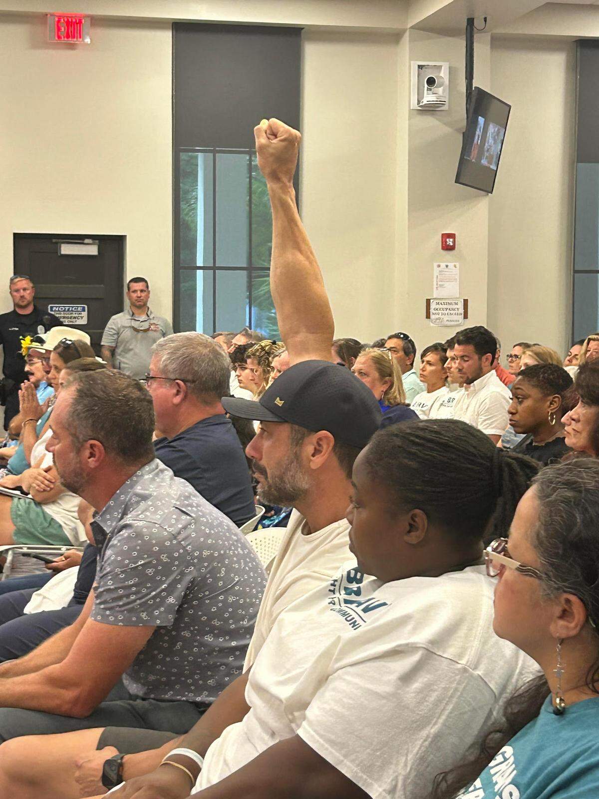 Nick Doll holds his fist in the air during a Tuesday, July 8, 2025, Key West City Commission meeting, where commissioners voted to re-enter into an agreement with U.S. Immigration and Customs Enforcement. (Photo by Gwen Filosa/Gwen Filosa Media Key West)