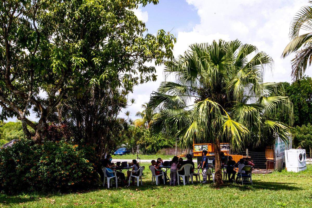 Migrant children gather in the yard of a migrant camp as Miami-Dade County Public School employees assist them with virtual learning during the coronavirus pandemic in South Florida on Thursday, May 21, 2020.