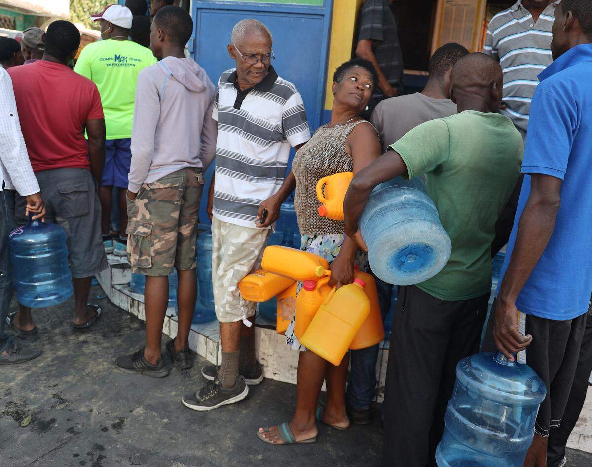 A woman plans to purchase water using old radiator coolant jugs as residents of Port-au-Prince, Haiti stood in line for essentials as Haiti’s political crisis disrupts the daily life of many Haitians while enduring the long wait and lines for gas and water throughout the capital city on Sunday, February 17, 2019.