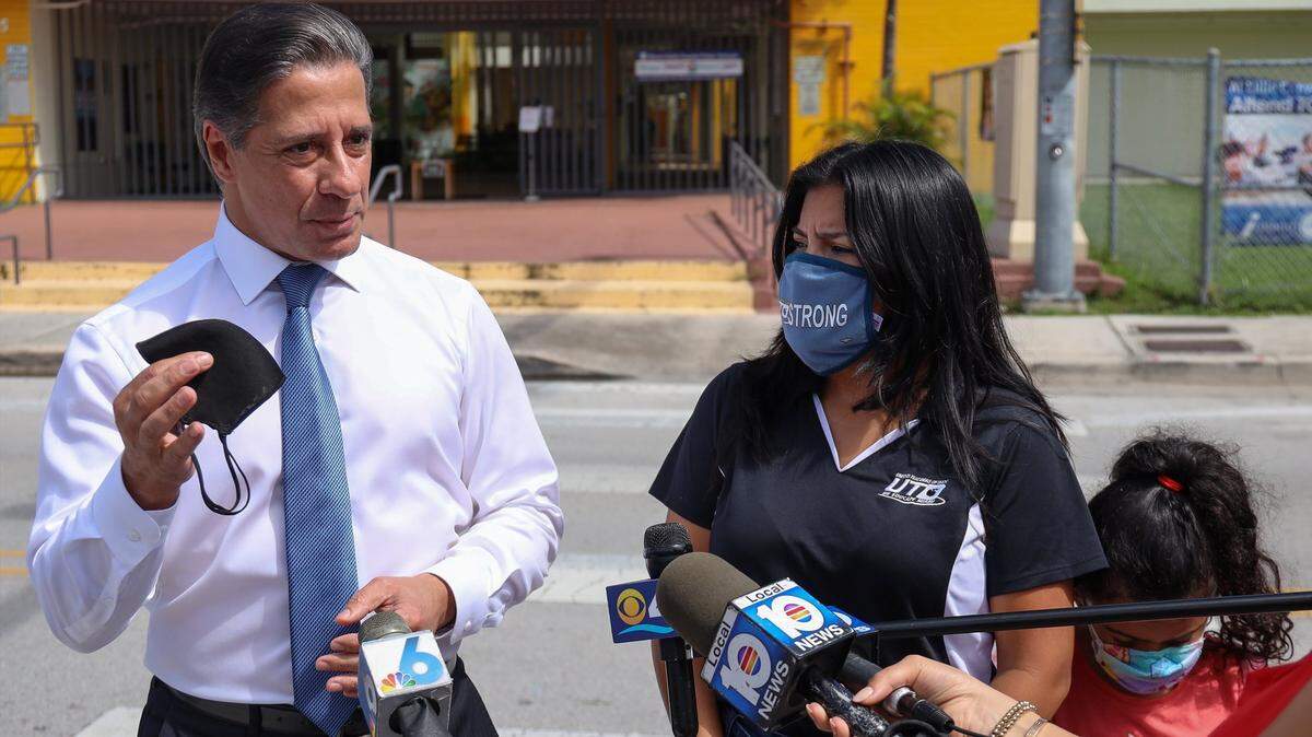 El superintendente escolar del Condado Miami-Dade, Alberto Carvalho, hace hincapié en la importancia del uso de mascarillas y de la vacunación contra el COVID-19 en un acto del sindicato de maestros en septiembre. La presidenta de United Teachers of Dade, Karla Hernández Mats, y su hija Naomi Mats, de 7 años, escuchan mientras él se dirige a los medios de comunicación.