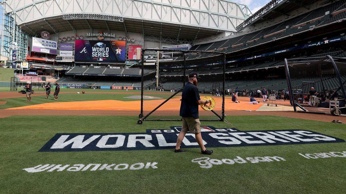 A member of the grounds crew works on the field as the Houston Astros stretch during the World Series Workout Day at Minute Maid Park on October 25, 2021 in Houston, Texas.