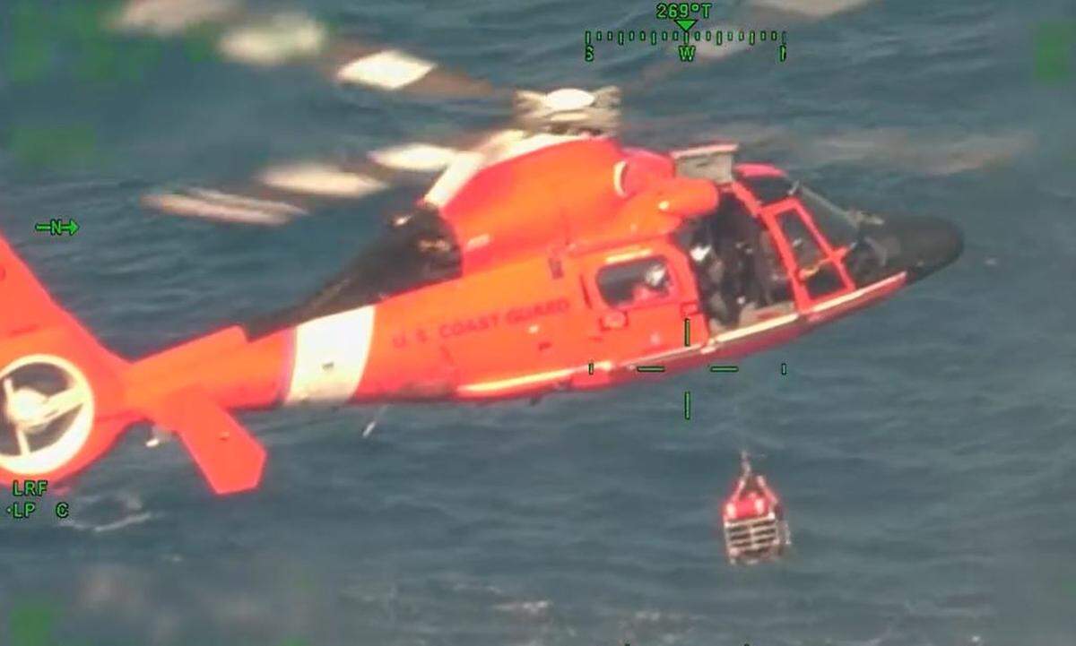 An Air Station Miami-based Coast Guard MH-65 helicopter hoists a person up to the aircraft using a rescue basket about 29 miles off St. Lucie Inlet Sunday, April 13, 2025. The agency rescued four people whose migrant smuggling vessel capsized on its way to South Florida from Bimini in the Bahamas. The search for five others was suspended.