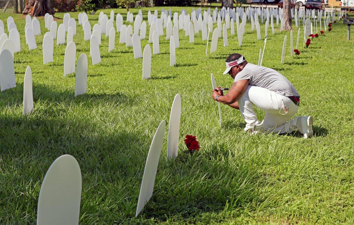 Eric Pitts, 47, honors his parents Dr. Dorothy Pitts and Marvin Council Pitts and brother Marvin Council Pitts Jr. as he writes their names on tombstones at Simonhoff Park in Liberty City Oct. 14, 2020. Five hundred plastic tombstones have been erected to represent people who have died from the coronavirus.