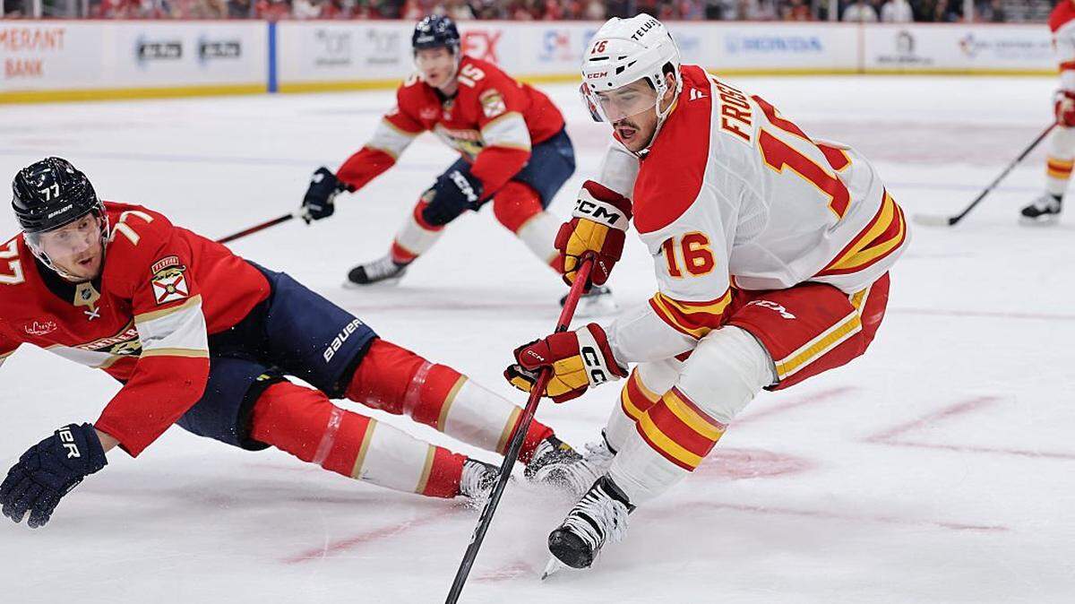 SUNRISE, FLORIDA - NOVEMBER 28: Morgan Frost #16 of the Calgary Flames controls the puck ahead of Niko Mikkola #77 of the Florida Panthers during the second period at Amerant Bank Arena on November 28, 2025 in Sunrise, Florida. (Photo by Carmen Mandato/Getty Images)