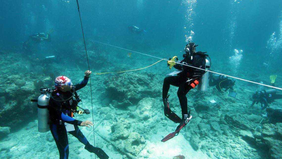 Rebecca Hunter and Ayeta Heatley work together to measure the position of an artifact in relation to the reference baseline on Molasses Reef off Key Largo on Friday, June 9, 2018.