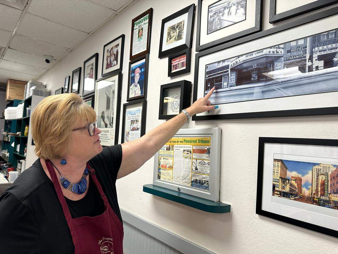 Tonya Gay, a veteran waitress at Lots of Lox in Palmetto Bay, points to a photo of the old Paramount Soda Shop that was on Southeast First Avenue and First Street in downtown Miami in the 1940s and ’50s. James Poulos owned the eatery. His grandsons Nick and Steve were co-owners of Lots of Lox.