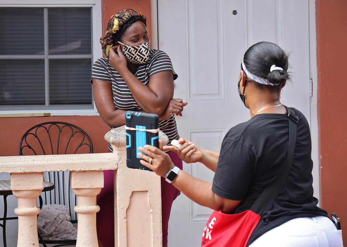 North Miami resident Kerene Jean-Juste, left, steps out her front as Ketty Toussaint Rene, right, canvasses for Unite Here, a Local 355 union office, as she knocked on doors while canvassing for Biden campaign in North Miami, Florida on Sunday October 4, 2020.