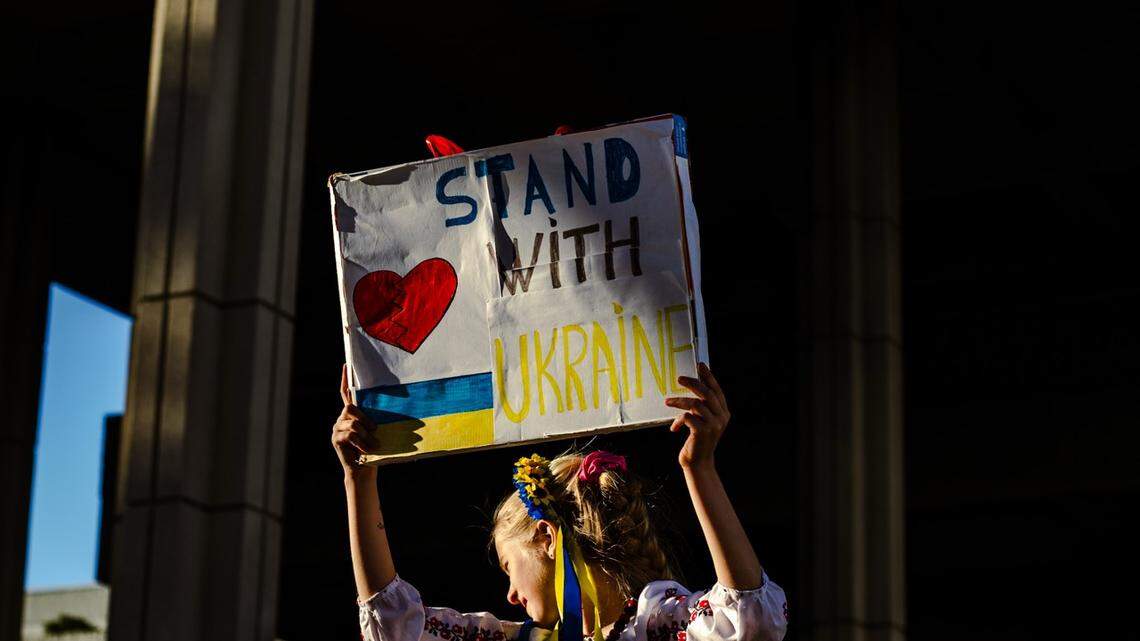 A girl in national Ukrainian attire holding up a placard in support of Ukraine at a Fort Lauderdale rally organized by the Ukrainian Association of Florida on Feb. 24, 2026.