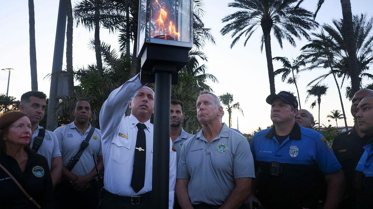 Miami Dade Fire Rescue Deputy Fire Chief of Emergency Operations Ray Jadallah extinguishes the symbolic flame during a ceremony with other firefighters and community members in front of where Champlain Towers South stood. Wednesday marked one year since the last of the 98 victims of the collapse was recovered.