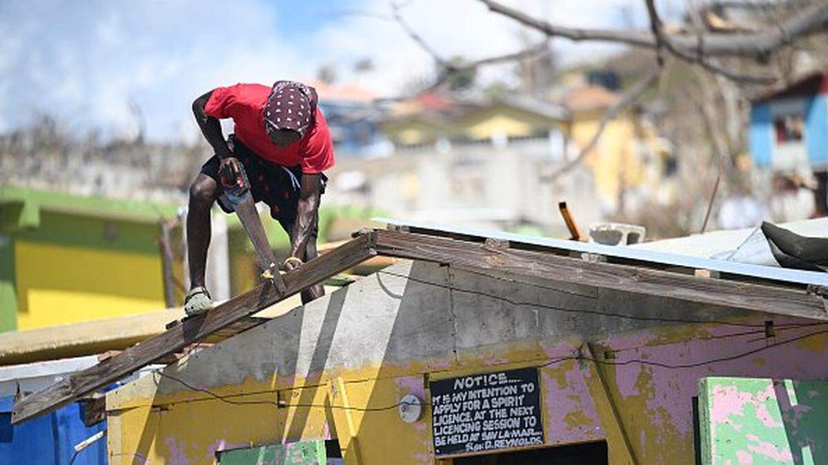 A man saws a piece of wood to repair the roof of a shop in Westmoreland, Jamaica, following the passage of Hurricane Melissa, on November 2, 2025. Planes and helicopters carrying humanitarian aid headed to Jamaica on October 31, three days after Melissa slammed into the island nation and killed at least 19 people. Information Minister Dana Morris Dixon told a briefing that authorities had "quite credible" reports of possibly five additional deaths but had not yet been able to confirm. (Photo by Ricardo Makyn / AFP) (Photo by RICARDO MAKYN/AFP via Getty Images)