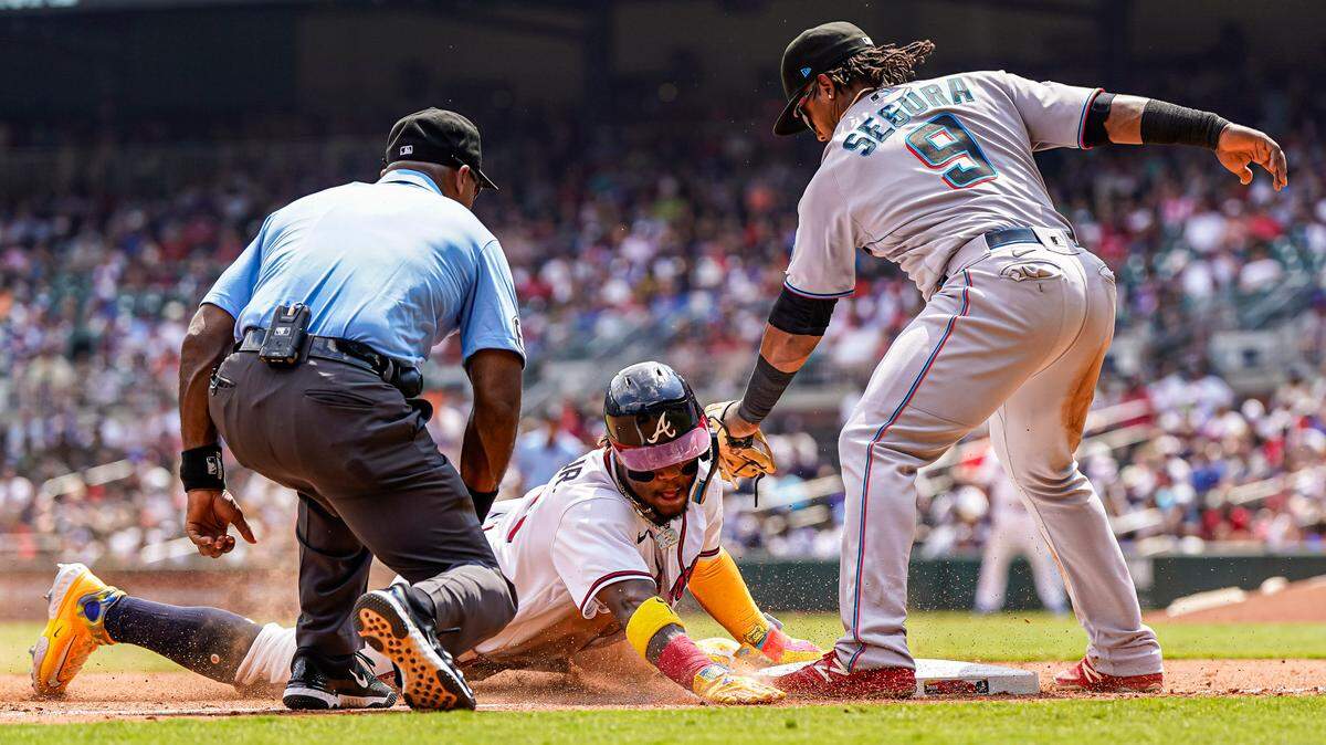 Jul 2, 2023; Cumberland, Georgia, USA; Atlanta Braves right fielder Ronald Acuna Jr. (13) steals third base under Miami Marlins third baseman Jean Segura (9) during the seventh inning at Truist Park. Mandatory Credit: Dale Zanine-USA TODAY Sports