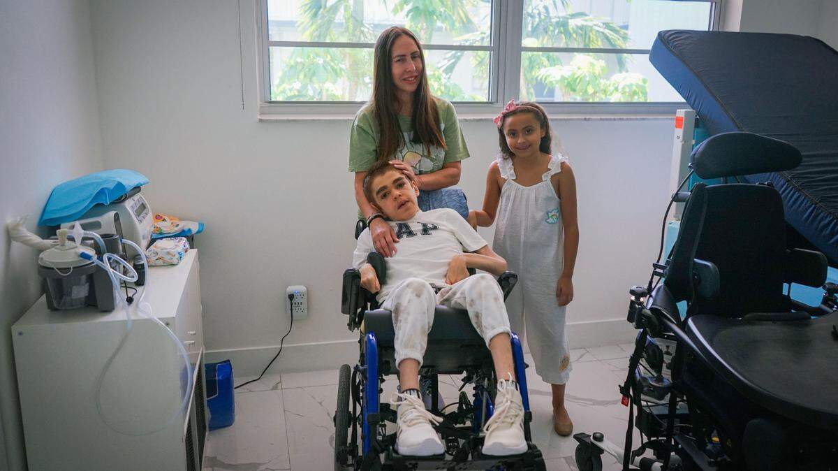 Kenia Cutie con su hija Chloe, de 9 años, y su hijo Charles, de 22, en el dormitorio de él. La movilidad de Charles está cada vez más limitada por una enfermedad rara, el síndrome de Sanfilippo.