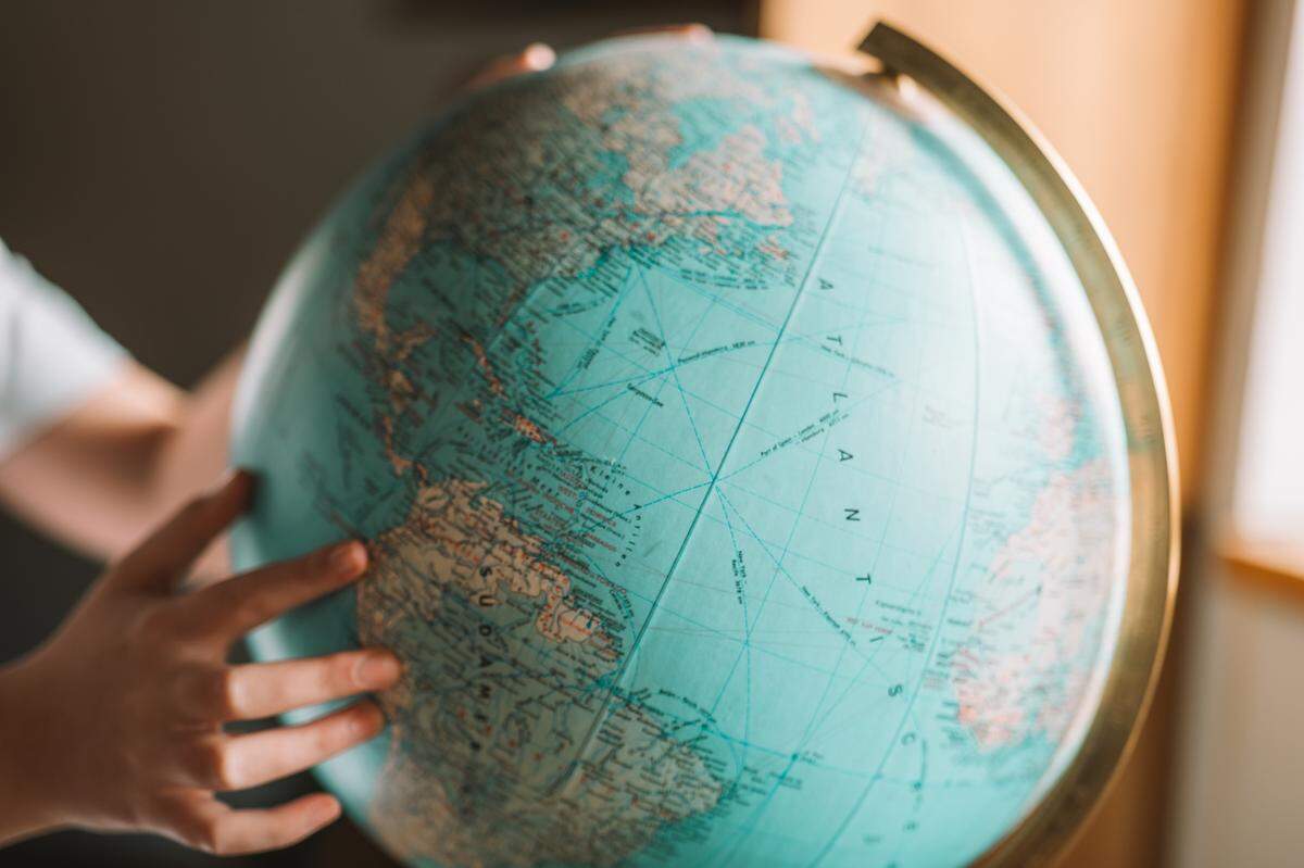 human hand points at globe