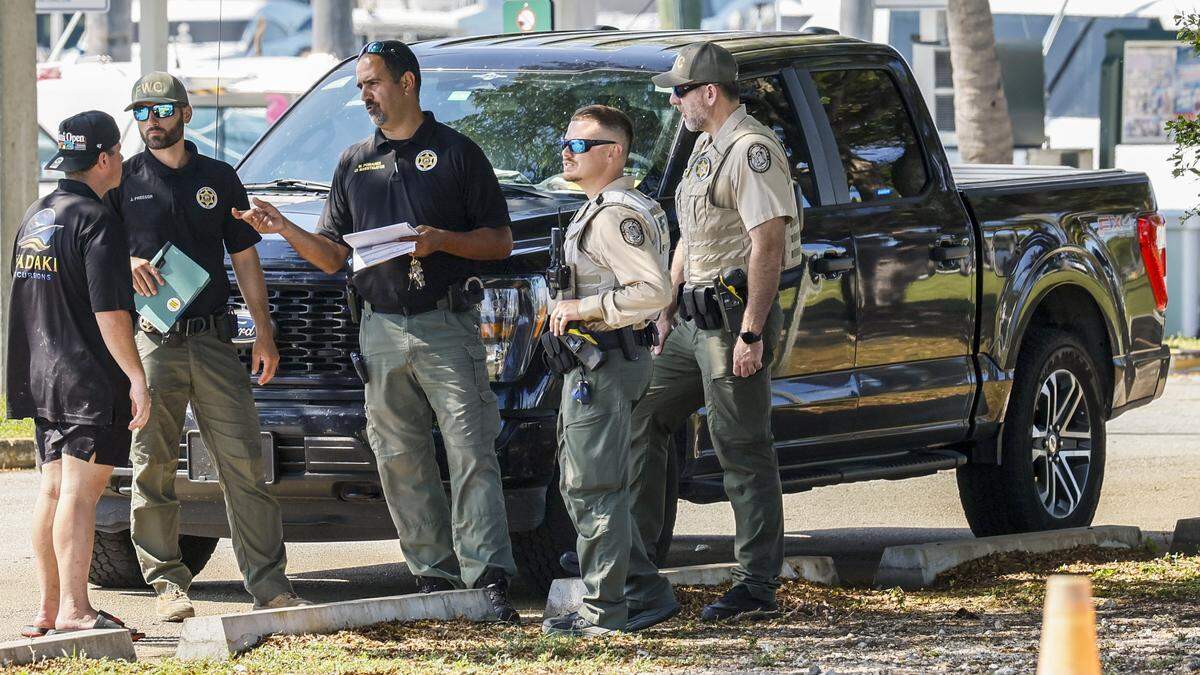 Law enforcement officers speak with a witness after 15 people were hospitalized in a possible boat explosion near Haulover Sandbar off Haulover Marina on Saturday, May 9, 2026.