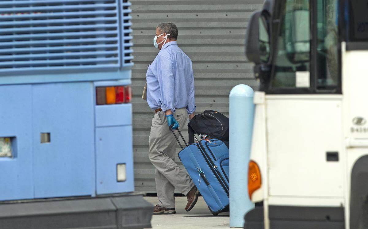 A Coral Princess cruise passenger walks to board the bus at PortMiami on Sunday, April 5, 2020 in Miami.