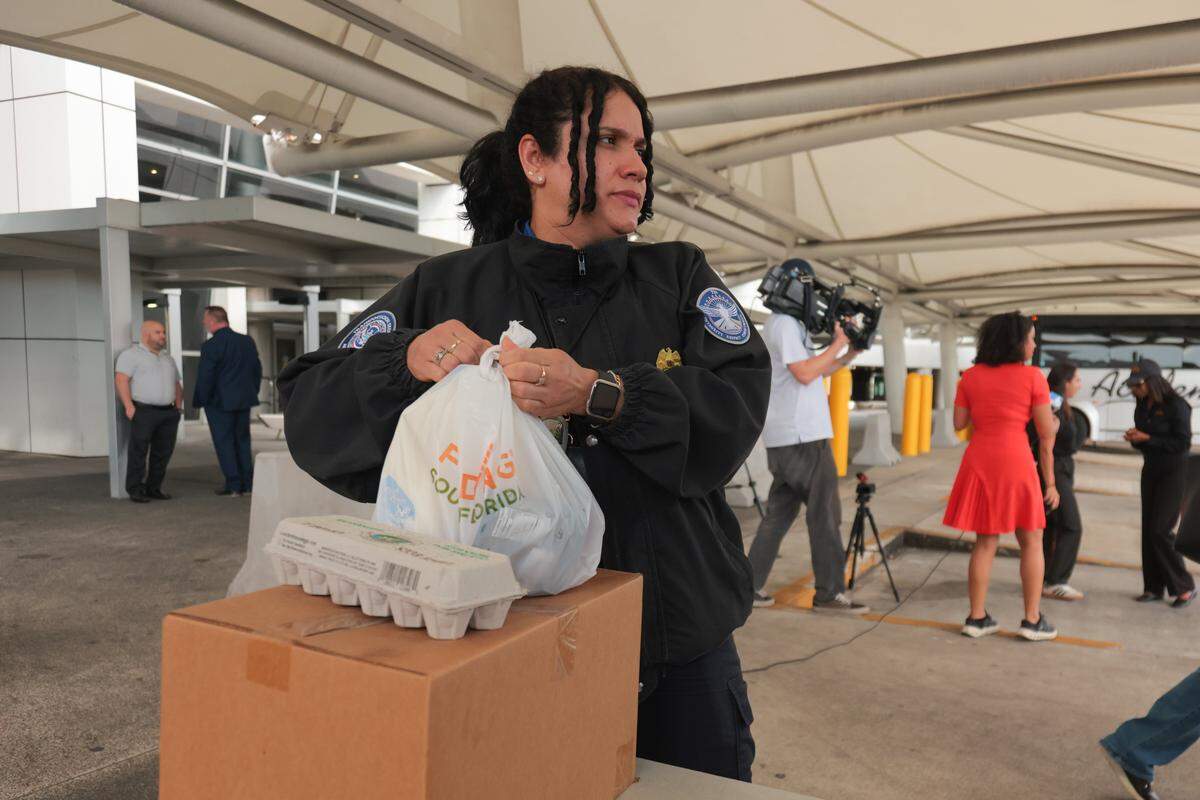 Dayana Perez, a Transportation Security Administration worker impacted by the federal government shutdown, collects food items at Miami International Airport in Miami, Florida, Friday, October 24, 2025.