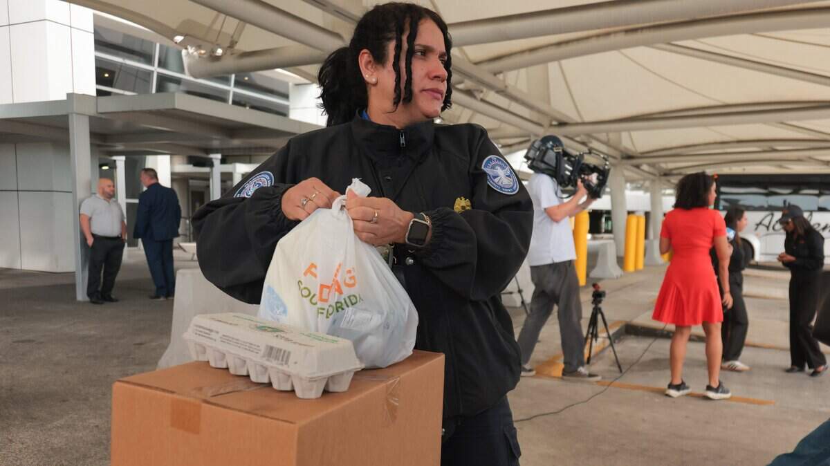 Dayana Perez, a Transportation Security Administration worker impacted by the federal government shutdown, collects food items at Miami International Airport in Miami, Florida, Friday, October 24, 2025.