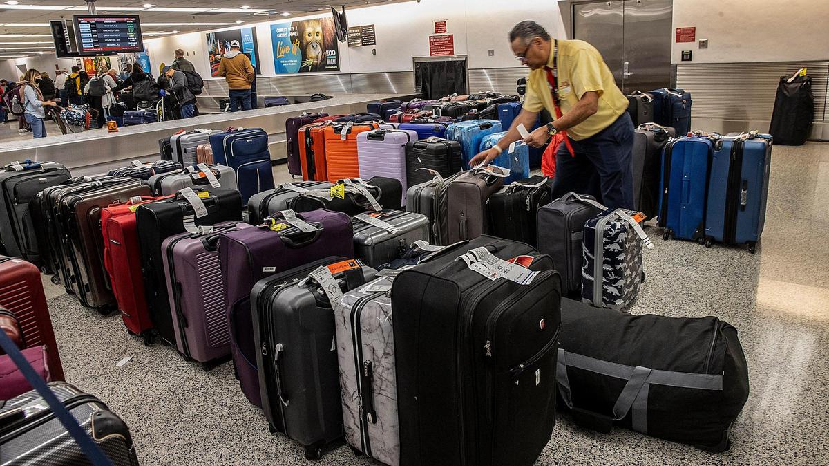 Enrique Borregales sorts through luggage piling up at Miami International Airport on Tuesday, Dec. 27, 2022., as many flights were canceled for Tuesday and Wednesday due to bad winter weather.