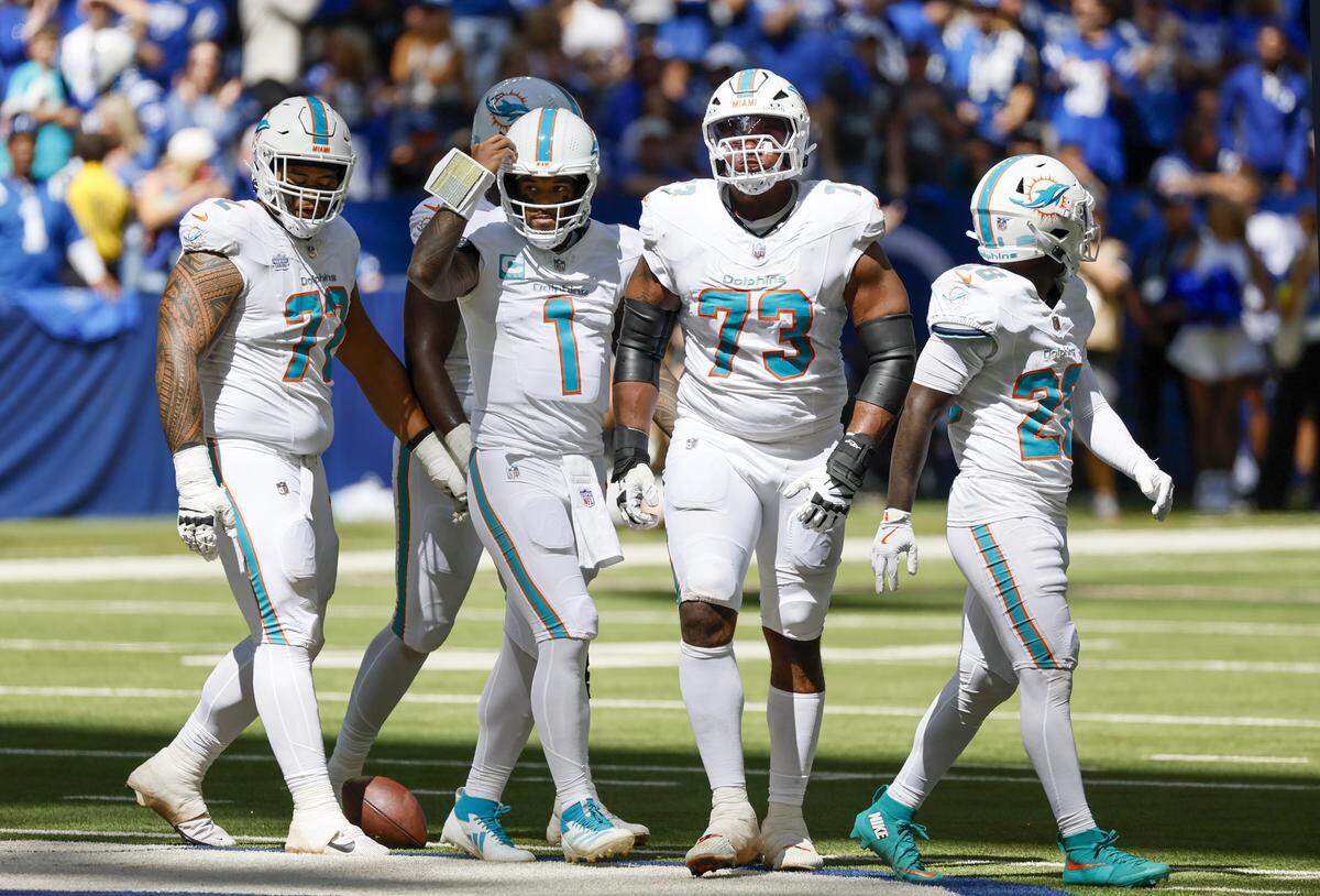 Miami Dolphins quarterback Tua Tagovailoa (1) stands alongside guard Jonah Savaiinaea (72), guard Austin Jackson (73), and running back De'Von Achane (28) during the first half of an NFL game against the Indianapolis Colts at Lucas Oil Stadium on Sunday, Sept. 7, 2025, in Indianapolis, Indiana.