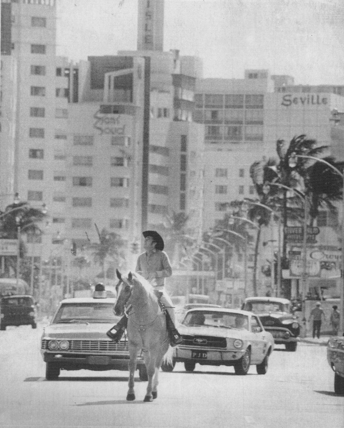 Bill Reno on horseback on Collins Avenue at Miami Beach, calling attention to the world rodeo championships at in December 1969.