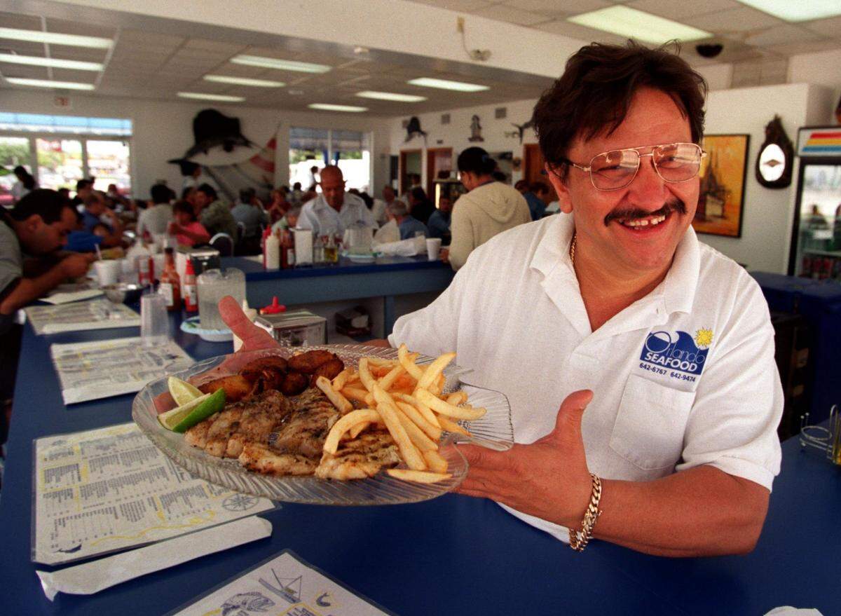 Orlando Gay, a Cuban exile, is Cynthia Bowles father. In this 2001 photo, he’s serving food at his Orlando’s Seafood restaurant in Miami.