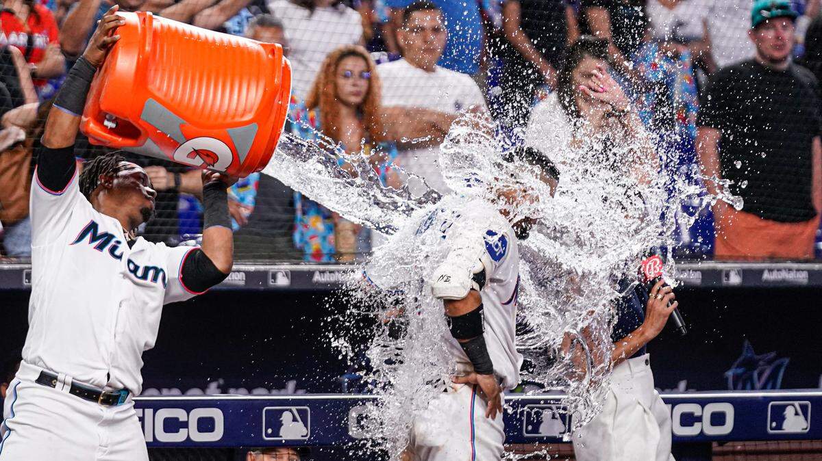 El tercera base de los Marlins Jean Segura  vierte el recipiente de Gatorade sobre el venezolano Luis Arráez, quien decidió el partido ante los Rockies de Colorado, el domingo 23 de julio de 2023 en Miami.