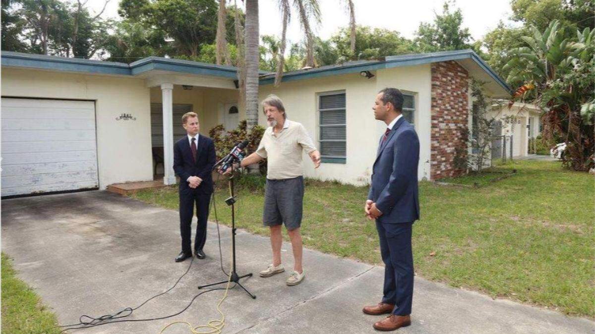 Dunedin homeowner Jim Ficken stands beside his attorneys, Andrew Ward (left) and Ari Bargil (right), during a news conference at his home. Ficken is suing the city of Dunedin for deciding to foreclose on his home due to accumulated fines for overgrown grass at nearly $30,000.