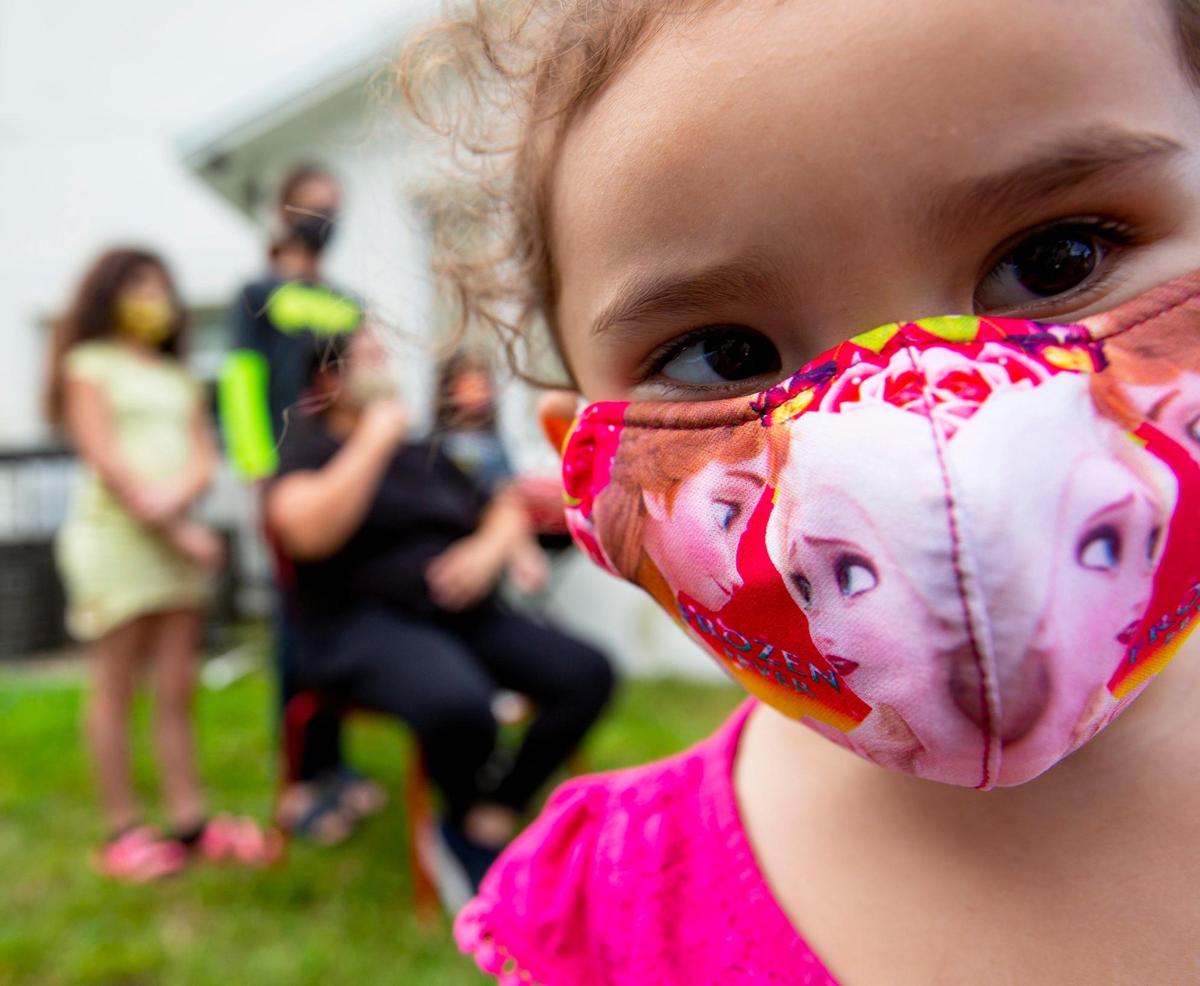 Single mother Kandy Gomez, 39, sits with her kids Christian Arias, 13, Jeslin Arias, 10, Gabriel Gomez, 7, in the background while her youngest daughter, Brianna Alvarado, 2, checks out the camera, outside their house in Liberty City.