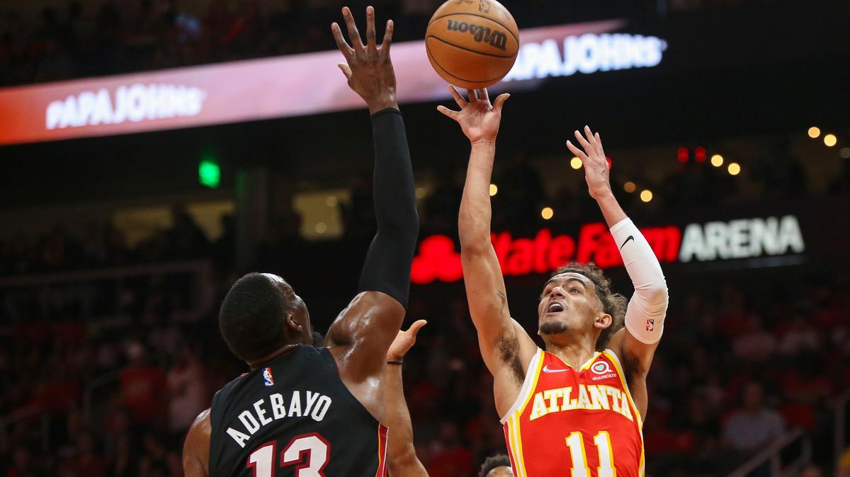 Atlanta Hawks guard Trae Young (11) shoots from between Miami Heat center Bam Adebayo (13) and guard Kyle Lowry during the first half of Game 3 of their first-round playoff series Friday, April 22, 2022, in Atlanta.