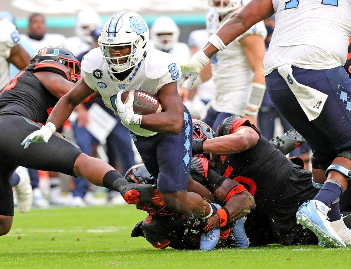 North Carolina Tar Heels Michael Carter (8) breaks through the Miami Hurricanes defensive line in the second quarter at Hard Rock Stadium In Miami Gardens, Florida, Saturday, December 12, 2020.