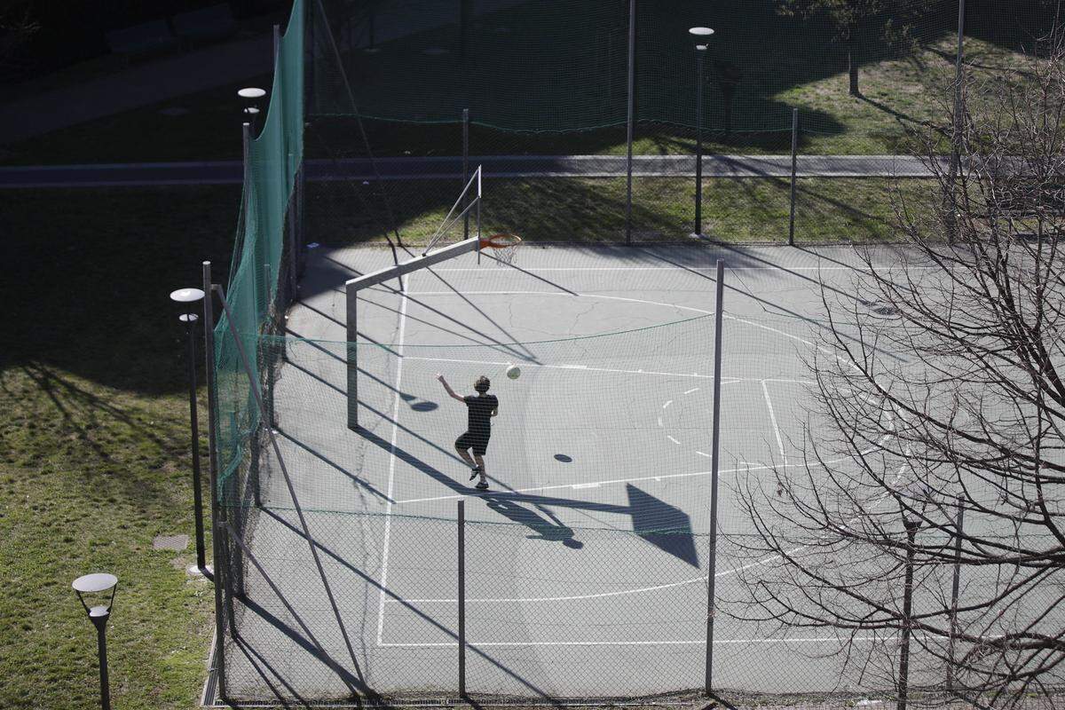 A boy plays basketball in a park in Milan, Italy, Wednesday, March 11, 2020. Italy is mulling even tighter restrictions on daily life and has announced billions in financial relief to cushion economic shocks from the coronavirus. For most people, the new coronavirus causes only mild or moderate symptoms, such as fever and cough. For some, especially older adults and people with existing health problems, it can cause more severe illness, including pneumonia. (AP Photo/Luca Bruno)