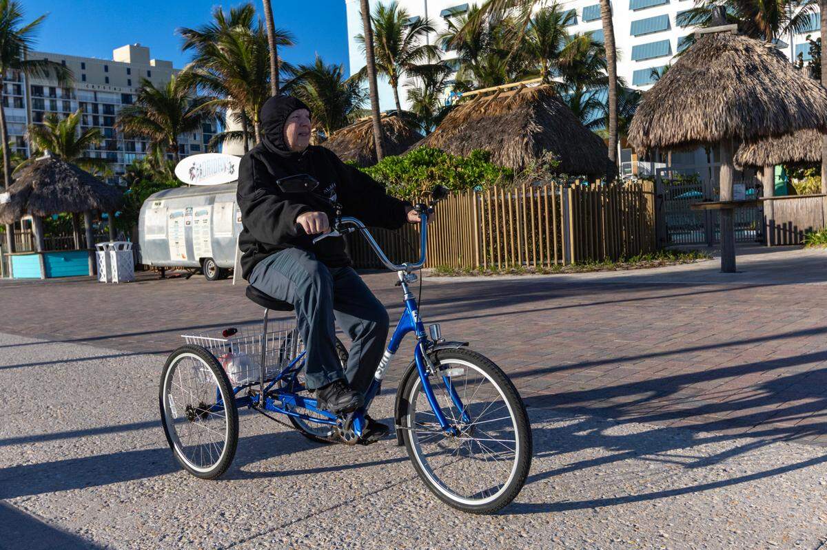 A man rides a tricycle down the Hollywood Beach Broadwalk under the cold weather on Tuesday, Jan. 30, 2024 in Hollywood, Florida.